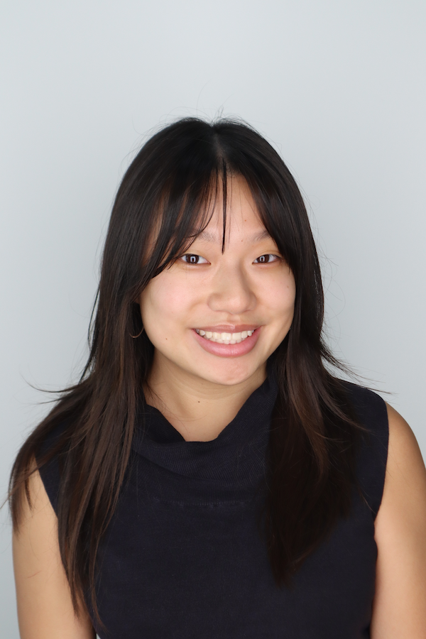 Emily headshot smiling wearing black tank against gray background